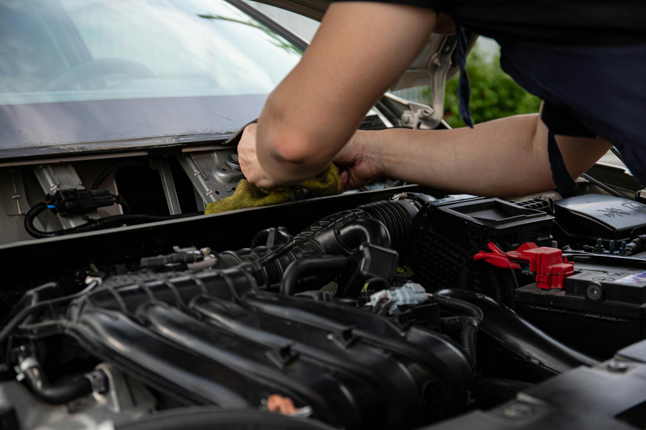 Mechanic working in engine bay on car AC system components