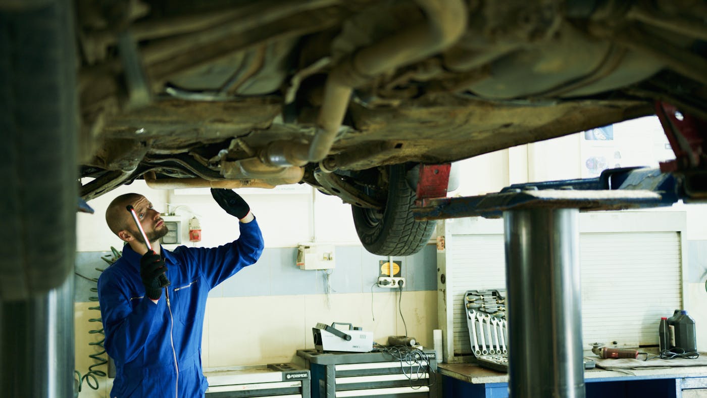 Mechanic examining transmission and drivetrain components from underneath